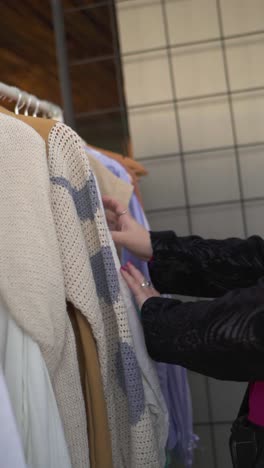 Closeup-of-womans-hands,-looking-at-clothes-on-hanger-and-choosing,-slow-motion