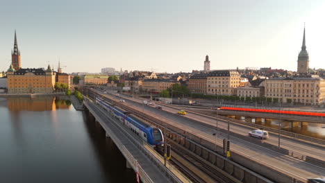 Train-crossing-Central-Bridge-toward-Gamla-Stan-in-Stockholm,-sunrise-aerial