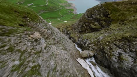 Aerial-FPV-View-Flying-Down-Mountain-River-towards-green-valley-landscape