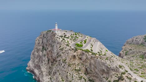 Drohnenansicht-Eines-Bootes-Im-Blauen-Meer-In-Der-Nähe-Des-Leuchtturms-Auf-Einer-Klippe,-Mallorca