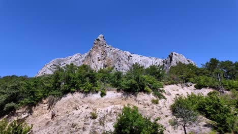 In-Sudak,-Crimea,-Russia,-a-rocky-mountain-peak-stands-tall-against-a-blue-sky