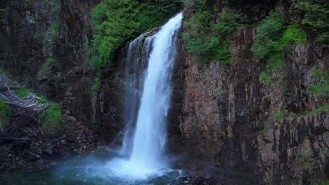 Scenic-stationary-shot-of-waterfall-flowing-into-water-base-in-Evergreen-Forest-in-the-Pacific-Northwest