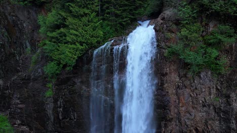 Toma-Panorámica-Ascendente-De-Una-Cascada-En-Un-Bosque-Siempre-Verde-En-El-Noroeste-Del-Pacífico.