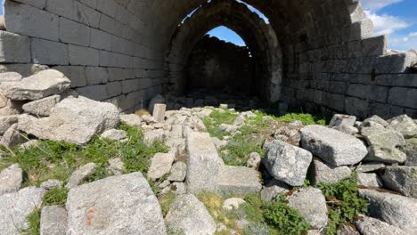 filming-of-the-hermitage-of-San-Pedro,-14th-century,-seeing-many-stones-on-the-ground,-we-appreciate-its-spectacular-vaults-with-rectangular-blocks-of-granite-we-see-a-blue-sky-with-clouds