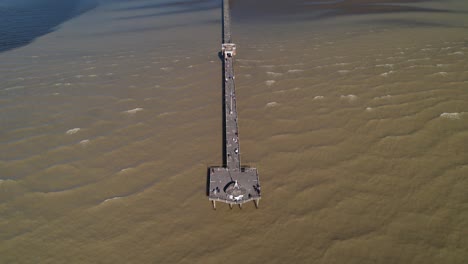 Aerial-Revealing-Tilt-Shot-of-Tourists-Walking-in-the-Sea-Walkway-over-the-La-Plata-River,-Punta-Lara,-Buenos-Aires,-Argentina