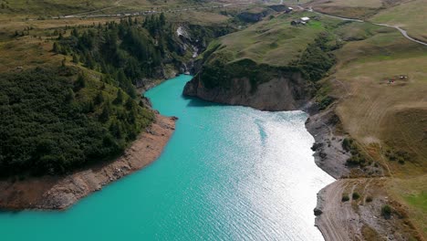 Vista-Aérea-Del-Lago-Mont-Cenis-Con-Sus-Aguas-Turquesas-Rodeadas-De-Verdes-Colinas-Y-Caminos-Sinuosos.