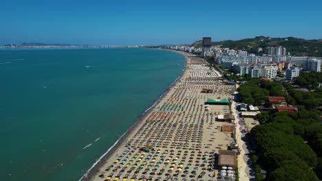 Playa-De-Durres-Con-Hoteles-Y-Complejos-Turísticos-A-Lo-Largo-Del-Mar-Adriático,-Sombrillas-Y-Tumbonas-En-Filas-Para-Tomar-El-Sol.