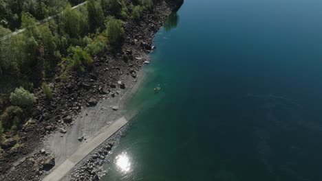 Kayaker-paddling-on-a-serene-lake-in-Røldal,-Norway-on-a-sunny-day,-aerial-view