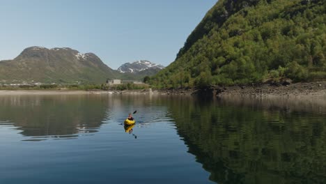 Kayakers-paddling-on-calm-Roldalsvatnet-lake-in-Roldal,-Norway-surrounded-by-lush-green-hills