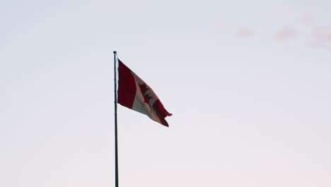 Large-Canadian-Flag-flutters-in-golden-light-against-pale-blue-sky