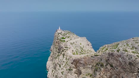 Birds-eye-view-of-steep-rugged-cliff-with-Formentor-Lighthouse-tower,-Spain