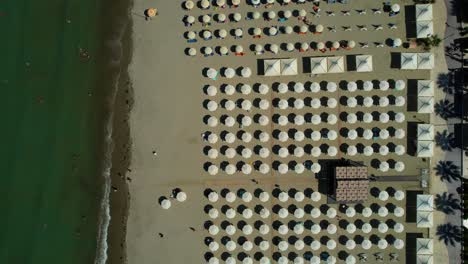 Fondo-De-Sombrillas-De-Playa-Alineadas-Frente-A-Hoteles-Y-Complejos-Turísticos-En-La-Playa-De-Arena-De-La-Costa-Adriática-De-Durres,-Albania