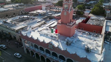 Aerial-descends-to-Mexican-flag-flying-on-city-hall-in-Merida,-Mexico