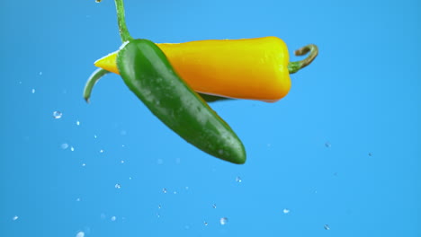 Pimientos-Verdes-Y-Amarillos-Chiles-Volando-En-El-Aire-Con-Gotas-De-Agua