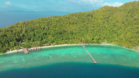 An-aerial-perspective-of-Kri-Island's-coastline-in-Raja-Ampat,-Indonesia,-with-lush-green-hills-and-turquoise-waters