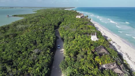 Flyover-dirt-road-on-narrow-strip-of-Caribbean-beach-near-Tulum,-MX