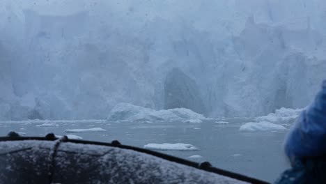 Bootsfahrt-Unter-Einem-Riesigen-Gletscher-An-Einem-Verschneiten-Tag,-Antarktisexpedition,-Zeitlupe