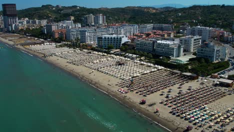 Großer-Sandstrand-An-Der-Adriaküste-Mit-Sonnenschirmen-Und-Sonnenliegen-Vor-Hotels-Und-Resorts-Zur-Buchung-In-Durres,-Albanien