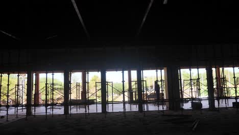 worker-erecting-scaffolding-inside-a-very-large-dark-hall-being-built-with-palm-trees-outside