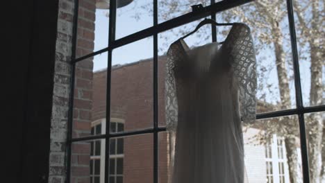 Slow-Motion-of-a-Brides-White-Wedding-Dress-Hanging-on-a-Window-Inside