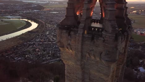 Crane-down-aerial-shot-next-to-William-Wallace-monument-in-Stirling,-Scotland,-during-blue-hour