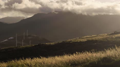 The-beautiful-dreamy-landscape-of-Madeira,-Portugal-during-sunset-with-windmills-and-mountains-in-the-background---Wide-shot