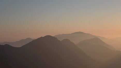 Panning-drone-shot-of-an-epic-sunset-over-the-hazy-Angeles-Mountains-north-of-Los-Angeles,-California