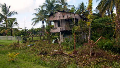 Una-Antigua-Casa-De-Madera-Elevada-Y-Abandonada-En-Una-Pequeña-Isla-De-Guyana,-Llena-De-Belleza-Verde-Y-Exuberante-Natural-Y-Situada-Junto-A-Una-Casa-De-Descanso---Plano-General