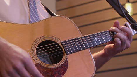 Man-playing-and-strumming-an-acoustic-guitar