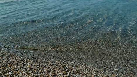 Shot-over-a-golden-sandy-shore-and-the-blue-sea-of-Mediterranean-sea-close-to-Thessaloniki,-Greece-in-Epanomi