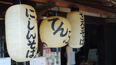 Cliente-Saliendo-De-Un-Restaurante-Con-Farolillos-Asiáticos-Tradicionales-Colgados-En-Kyoto,-Japón-Iluminación-Suave-En-Cámara-Lenta-4k