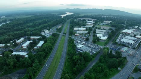 Aerial-trucking-pan-across-highway-leading-off-into-distance-of-mountains-with-lush-green-area-between-road