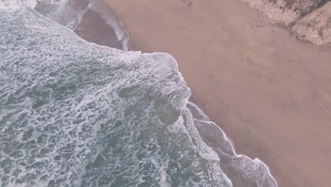 Olas-Del-Pacífico-Rompiendo-En-La-Playa-Junto-Al-Acantilado---Drone-Aéreo-4k