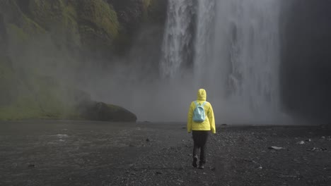 Muestra-A-Una-Mujer-Caminando-Hacia-Una-Cascada-Gigante-En-Islandia