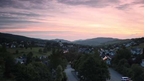 Amplia-Panorámica-Sobre-El-Balneario-Montañoso-De-Grafschaft-En-La-Región-De-Deportes-De-Invierno-De-Sauerland,-Alemania,-Durante-La-Puesta-De-Sol-Con-Un-Colorido-Cielo-Nublado-Iluminado-De-Color-Púrpura-Y-Naranja