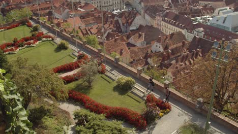 Tourists-walking-around-Schlossberg-castle-in-Graz,-with-city-roofs-in-the-background