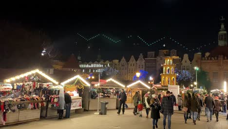 Slowmotion-people-walk-around-the-square-at-the-Christmas-market,-colourful-stands-with-Christmas-exhibitions