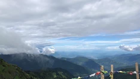 Tages-Zeitraffer-Von-Ziehenden-Wolken-über-Hügeln-Mit-Gebetsfahnen-Im-Vordergrund