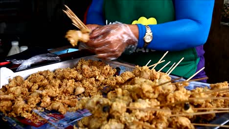 ANTIPOLO-CITY,-PHILIPPINES-–-JULY-12,-2019:-A-street-food-vendor-puts-deep-fried-chicken-intestine-into-barbecue-sticks-and-sells-them-at-her-makeshift-food-stall