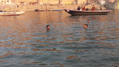 Tracking-Shot-of-Men-Swimming-in-the-Ganges-River-at-Varanasi,-Benares,-Banaras,-Kashi,-Uttar-Pradesh,-Lucknow,-India