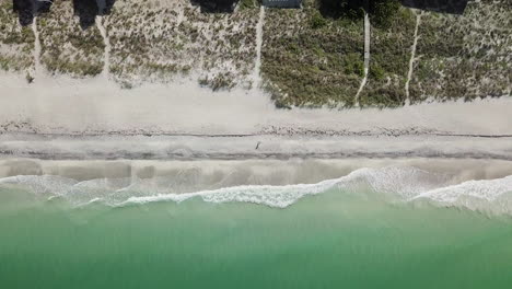 Muestra-De-Arriba-Hacia-Abajo-De-Casas-De-Playa,-Un-Helicóptero-Vuela-Hacia-Adelante-Para-Revelar-La-Playa-De-Agua-Teal