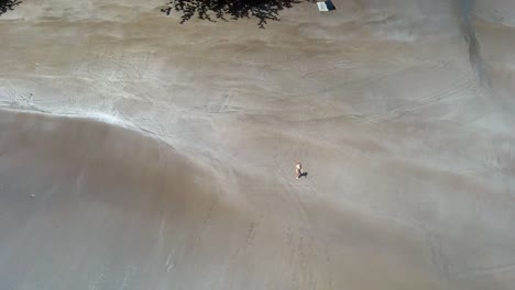 Aerial-view-from-top-of-young-woman-walking-on-a-empty-beach,-São-Tomé-Island