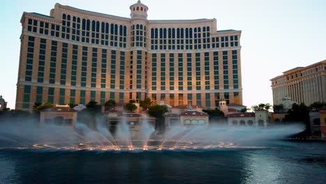 Wunderschöne-Aufnahmen-Des-Bellagio-Casino-Hotels-Vor-Dem-Hotel,-Die-Einen-Springbrunnen-Bei-Sonnenuntergang-Zeigen,-Las-Vegas