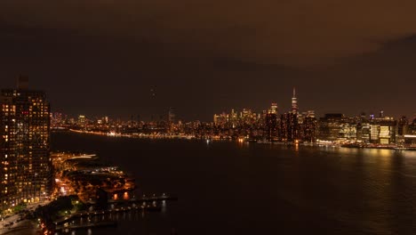 Time-Lapse-of-traffic-in-New-York-City-on-three-levels,-Air,-Ground,-Water-at-night,-with-One-World-Trade-Center,-FDR-Drive,-East-River-in-the-foreground-at-night,-filmed-from-Long-Island-City