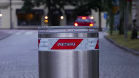 Handheld-Close-Up-of-a-Pilomat-Road-Blocker-With-Red-Flashing-Light-With-Cars-In-The-Background-Driving-By-The-Road-as-Food-Delivery-and-Regular-Cars-in-The-City-of-Borås