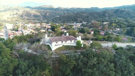 Aérea:-Toma-Panorámica-Aérea-De-La-Fortaleza-En-La-Cima-De-Una-Colina-Rodeada-De-árboles-Y-Con-Vista-A-La-Ciudad