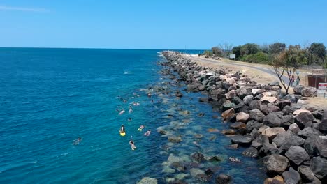 Arial-view-of-a-group-of-children-enjoying-a-day-out-swimming-at-a-local-water-spot-under-the-supervision-of-adults