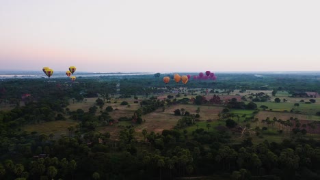 Aerial-shot-of-colourful-hot-air-balloons-lifting-off-at-dawn-in-Bagan,-Myanmar