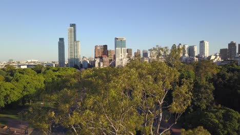 Aerial-rising-of-Bosques-de-Palermo,-a-Persian-column-and-Buenos-Aires-skyline-in-background