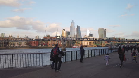 Londoners-walking-past-Millenium-Footbridge-in-front-of-the-skyline-with-Fenchurch-and-Leadenhall-iconic-buildings,-on-the-first-day-after-Brexit